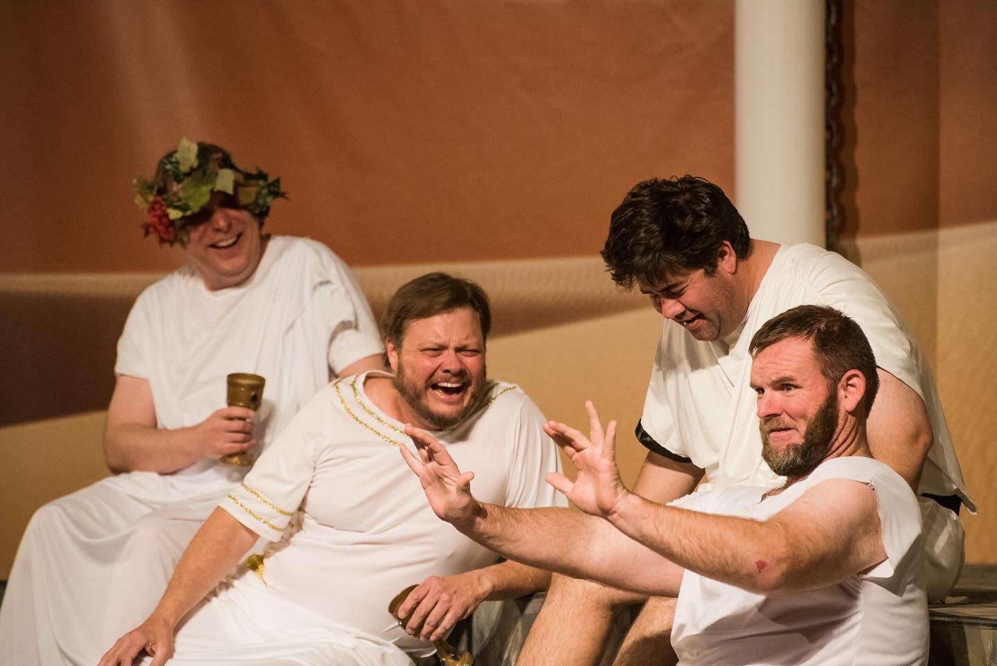 Men in white garments are seen laughing and chatting close together