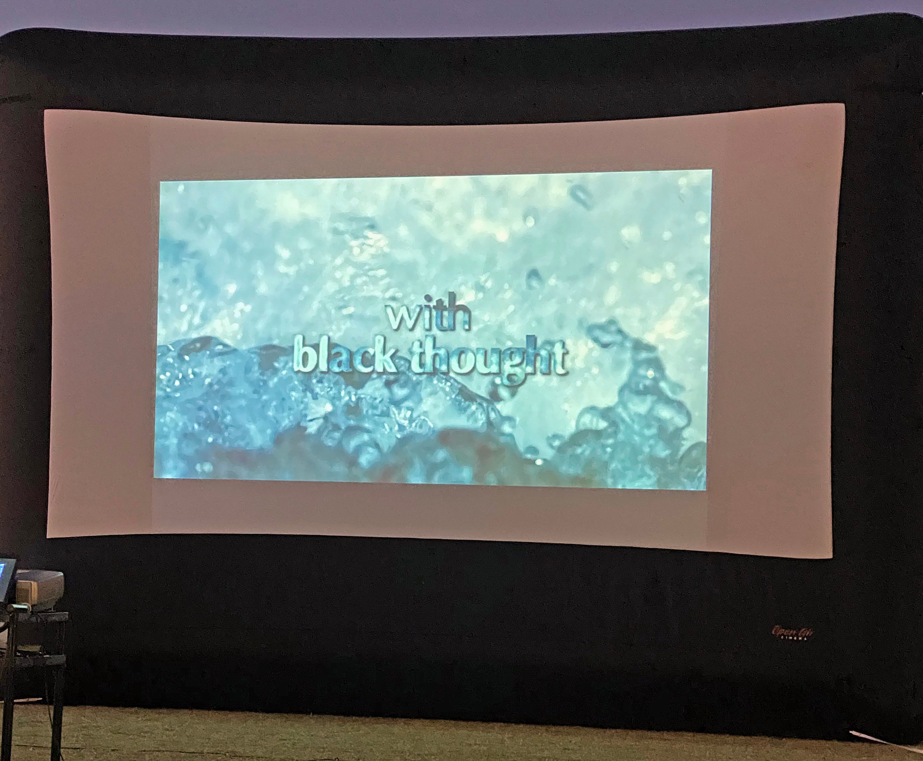 a projection screen shows a watery background with the words "With black thought"
