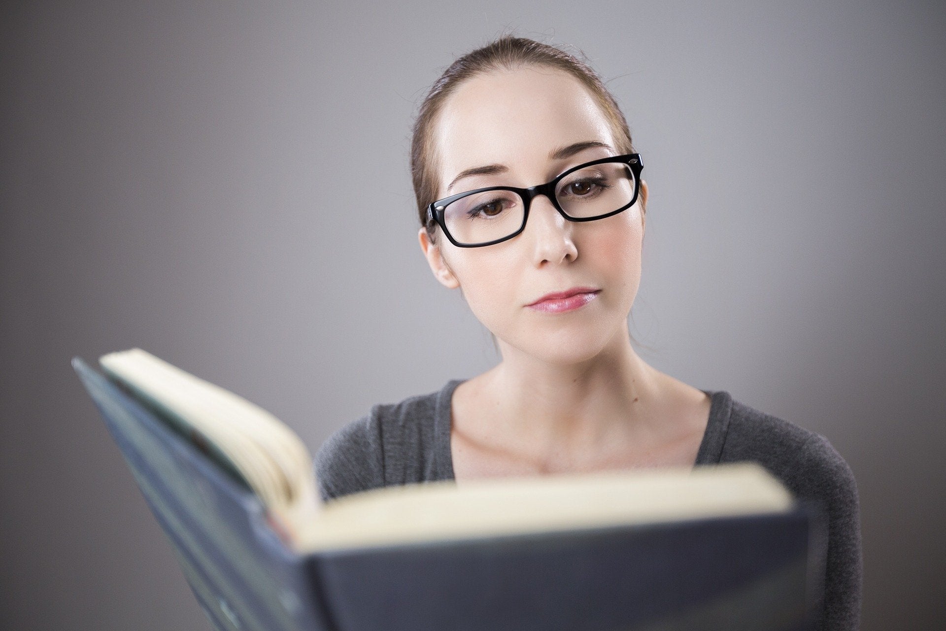 A woman holding up a book and reading 