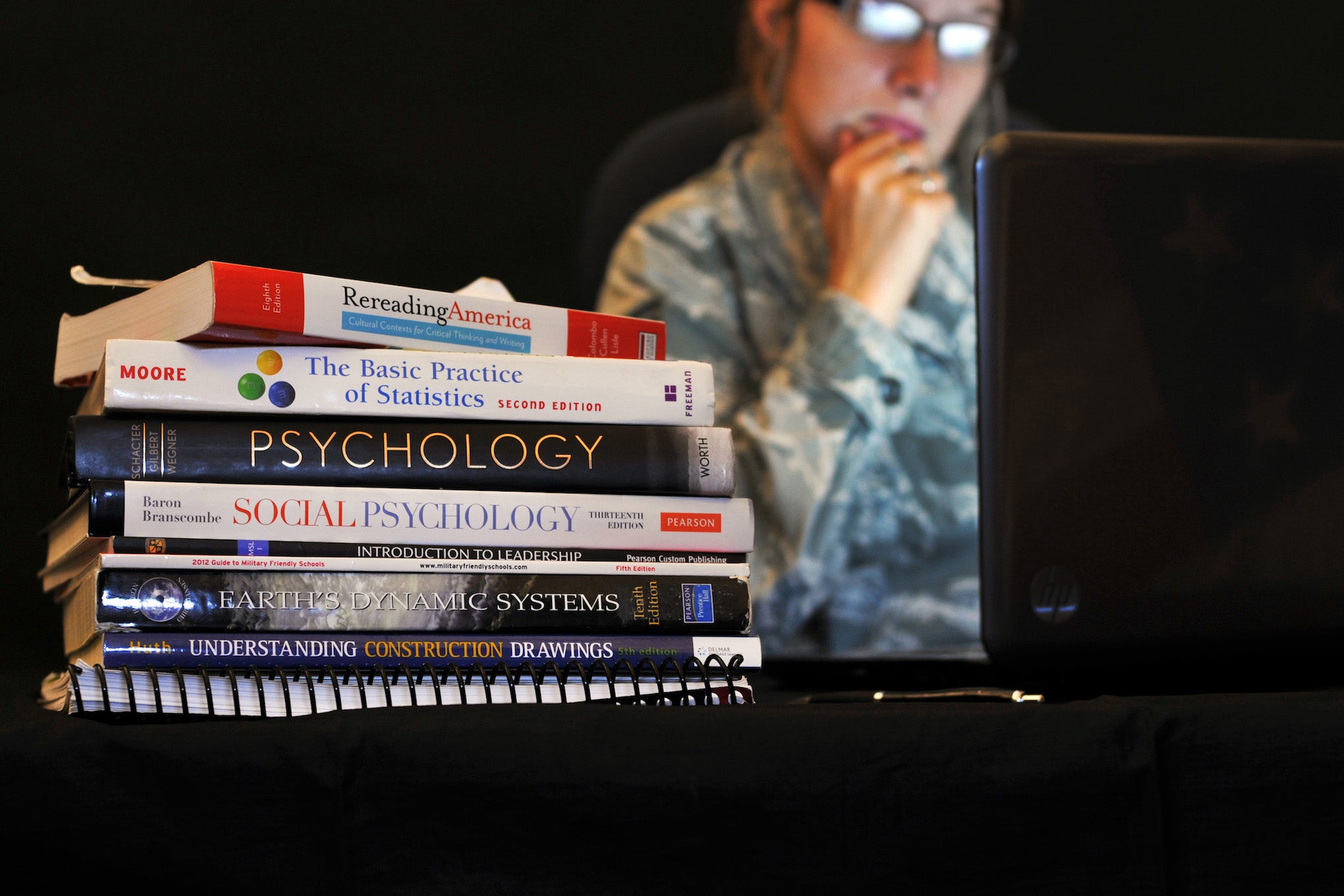 Photo Credit: U.S. Air Force college books in front of a soldier looking into a computer.