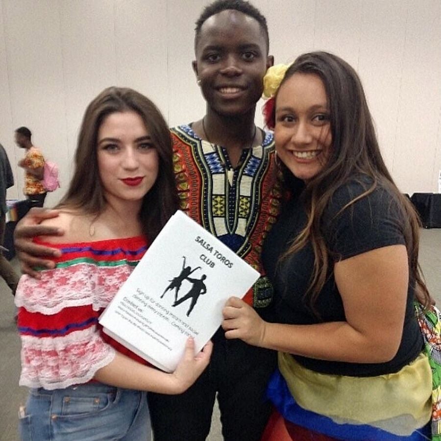Vanessa Alcazar and Jessica Ramirez pose with another member of the new campus Salsa Toro club at AWC. two women and a man pose with a salsa dance booklet