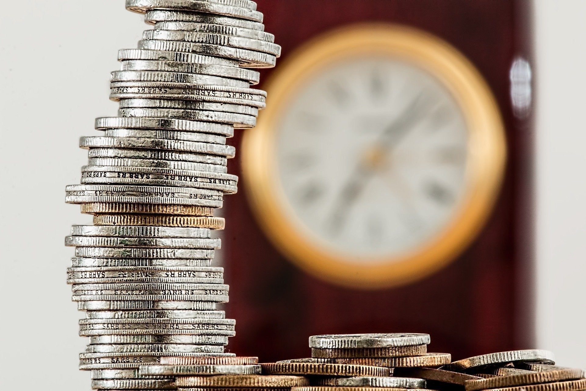 Photo illustration courtesy of stevepb, pixabay.com Quarters are stacked in an imperfect column with a gold-accented clock blurred in the background