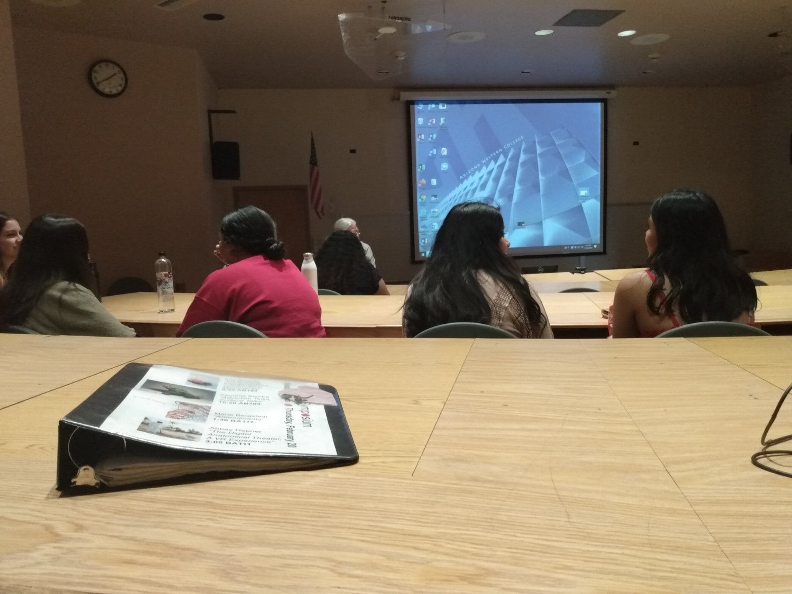 A seat at a table--multiple rows of people in front of a projector