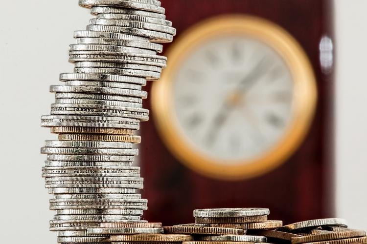 Photo illustration courtesy of stevepb, pixabay.com Quarters are stacked in an imperfect column with a gold-accented clock blurred in the background