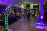 people stand in a colorfully lit (purple and green) cafeteria party.