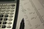 A calculator and pen sit atop a paper used for finance checking 